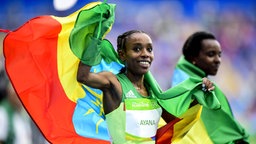 Die Äthiopierin Almaz Ayana jubelt mit einer Äthiopien-Flagge. © Imago/Bildbyran