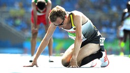 Der deutsche 5.000 m Läufer Florian Orth kniet erschöpft auf dem Boden. © Witters Foto: James Lang
