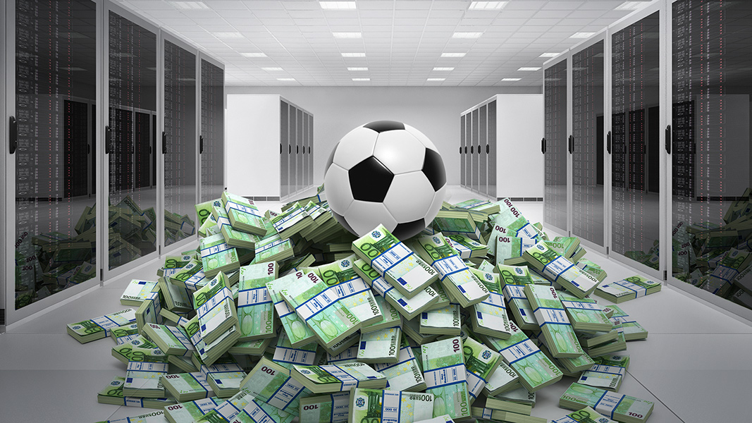 Ein Fußball liegt in einem Serverraum auf auf einem Berg von Geldscheinen.