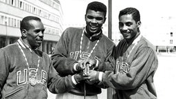 Die amerikanischen Boxer (l-r) Edward Crook, Cassius Clay (später als Muhammad Ali bekannt) und Wilbert McClure freuen sich im August 1960 bei den Olympischen Sommerspielen in Rom über ihre Goldmedaillen. © picture-alliance / dpa 