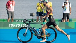 Der deutsche Triathlet Jonas Schomburg läuft im Odaiba Marine Park mit dem Fahrrad in der Wechselzone. © dpa-Bildfunk 