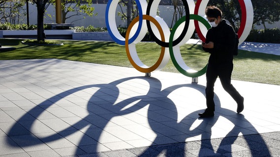 Die Olympischen Ringe vor dem Nationalstadion in Japan werfen Schatten. © picture alliance / kyodo / dpa 