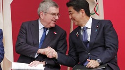 Shinzo Abe, Ministerpräsident von Japan, und IOC-Präsident Thomas Bach (l.) schütteln sich die Hand. © picture alliance/Koji Sasahara/AP/dpa Foto: Koji Sasahara