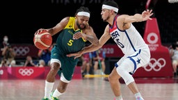 Patty Mills von Australien dribbelt an Devin Booker aus den USA mit dem Basketball vorbei. © imago images/AAP Foto: JOE GIDDENS
