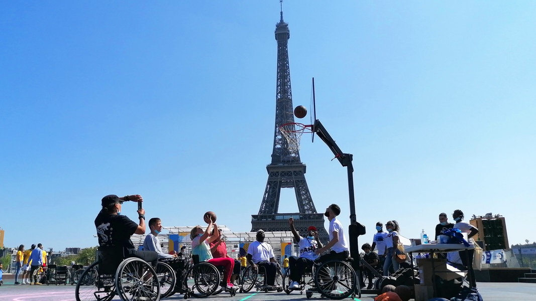 Menschen in Rollstühlen spielen Basketball vor dem Eifelturm in Paris.