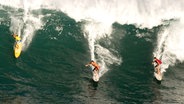 Drei Surfer reiten eine Welle vor Hawaii © imago/ZUMA Press 